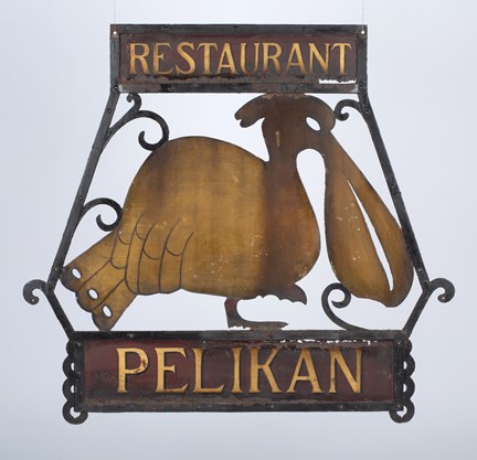 Skylt med texten "Restaurant Pelikan" som också föreställer en pelikan i guld-brons-färg