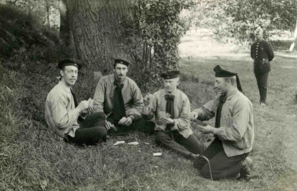 Fyra personer sitter och spelar kort i gräset