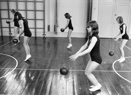 Flickor studsar bollar i gymnastiksal