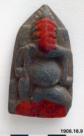 Liten stenfigurin med rött lack
