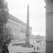Utsikt över Slottsbacken. Högvakten passerar obelisken på Slottsbacken. Nationalmuseet i fonden