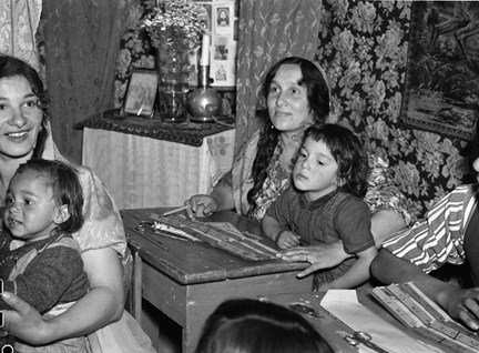 Interiörbild från den första skolan för romer som just öppnats i familjen Taikons tält vid romernas läger vid Lilla Sköndal i Gubbängen. Till höger eleven Singoalla Taikon med sin son i knät.