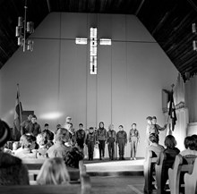 Scoutceremoni i Missionskyrkan i Enskede. Grupp av scouter och ledare flankerade av fanbärare