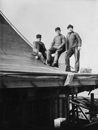 Svart-vit bild med tre män på ett koppartak, två sittande och en stående. De bär varma mössor och arbetskläder. Bilden är fotograferad snett underifrån.