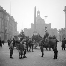 Slottsbacken. Kungliga vagnar dragna av hästar. I bakgrunden Obelisken samt Storkyrkan