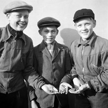 Tre pojkar visar upp bombsplitter efter den sovjetiska bombfällningen över Eriksdalsområdet 1944.
