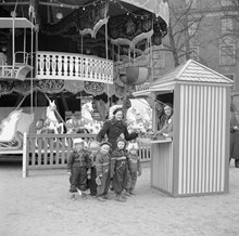 Kungsträdgården. Tivoli/karusell i samband med Röda Korset-veckan. En kvinna med en grupp barn vid biljettkassan