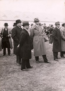 Kristinebergs Idrottsplats invigs. Män i överrock och hatt lyssnar på invigningstalet. 25 maj 1933