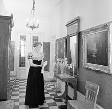 Hovfröken Brita Steuch i sin hovdräkt står i hallen till sin bostad på Sturegatan 20