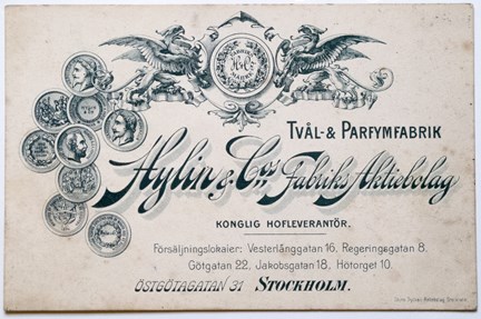 Svartvitt reklamtryck med medaljer, emblem och text.