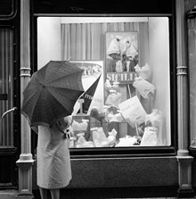 Västerlånggatan. En regnig dag under Västerlånggatans ""Vår festival"". En kvinna tittar på underkläder och turistaffischer i ett skyltfönster. Folk uppmanades att rösta på den affisch som lockar mest