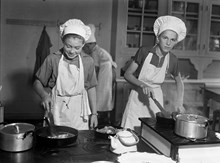 Folkskola på Lidingö. Pojkar lär sig laga mat, baka och hushållsskötsel. Porträtt av två pojkar i förkläden och kockmössa