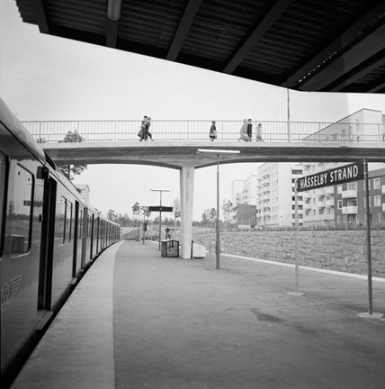Ett tåg vid perrongen, människor på gångbro.