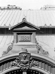 Hötorgshallen före rivningen 1954. Byggnadsdetaljer vid taket med årtalet 1882 då saluhallen byggdes och vapensköld med St. Erik. En skrattmås ser ut över torget