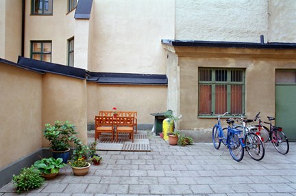 Bakgård med cyklar, uteplats och blomkrukor
