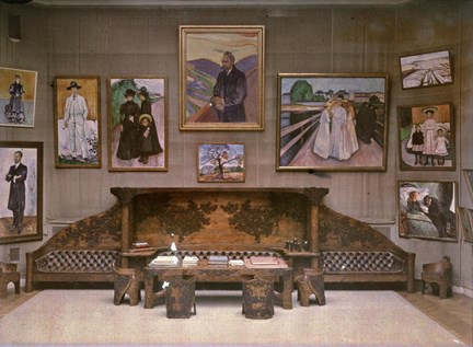 Ett tidigt färgfotografi med Edvard Munchs målningar som hänger tätt på väggen vid den stora soffan.