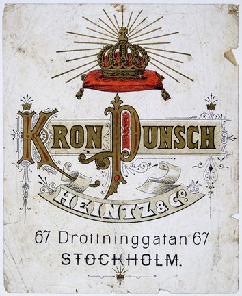 Etikett tryck i rött, svart och guld med bild av en krona samt text.