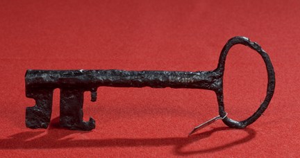 Nyckel från medeltiden fotograferad mot röd bakgrund. 