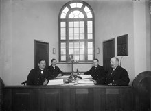 Porträtt av 4 uniformsklädda herrar sittande vid bord
