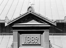 Hötorgshallen före rivningen 1954. Byggnadsdetaljer vid taket med årtalet 1882 då saluhallen byggdes. En skrattmås ser ut över torget
