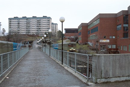 Bredängs centrum med  gångbro och förbisusande tunnelbanetåg
