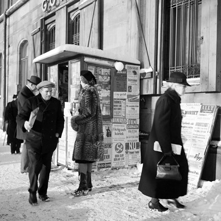 Människor passerar tidningskiosk.