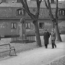 Författarna Bo Bergman och Per Wästberg (militärklädd) på Klara kyrkogård vid gravstenen över Anna-Maria Lenngren