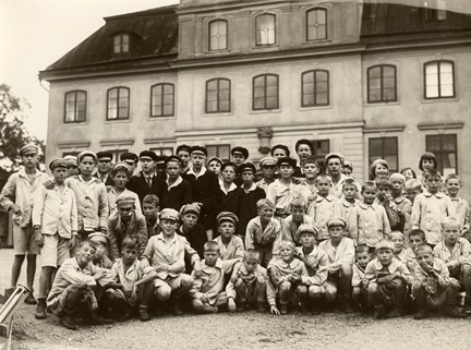 Svartvitt fotografi på barn samlade utanför barnhuset i Kristineberg