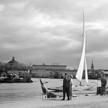 Segelbåt på Ladugårdslandsviken från Strandvägskajen. Skeppsholmen med krigsfartyg i bakgrunden